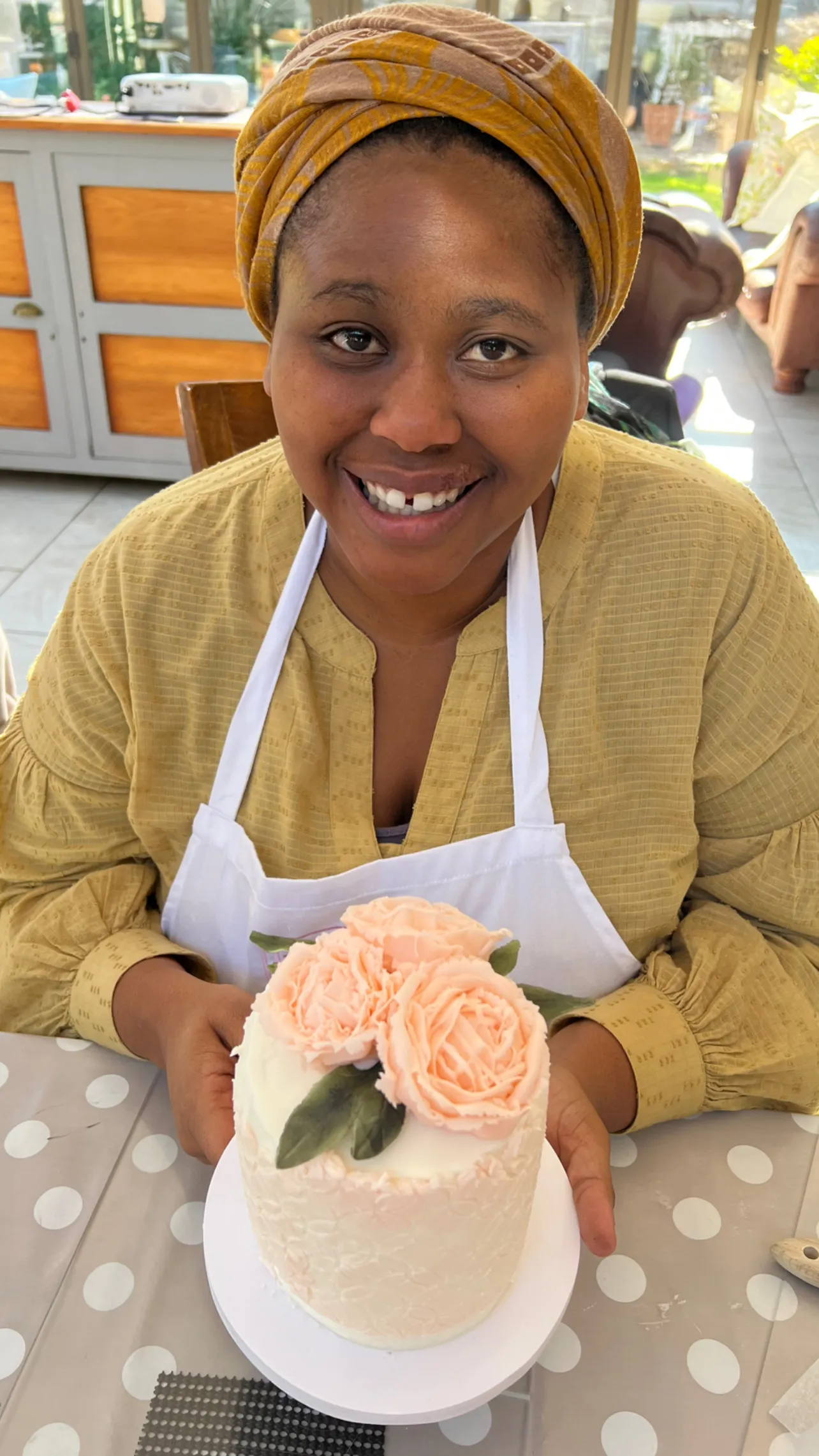 A smiling student holds the buttercream cake she decorated with peach roses in one of Grace's classes